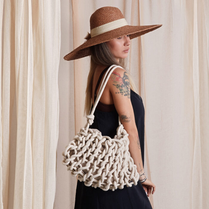 girl holds a handmade knitted shoulder bag in natural white color