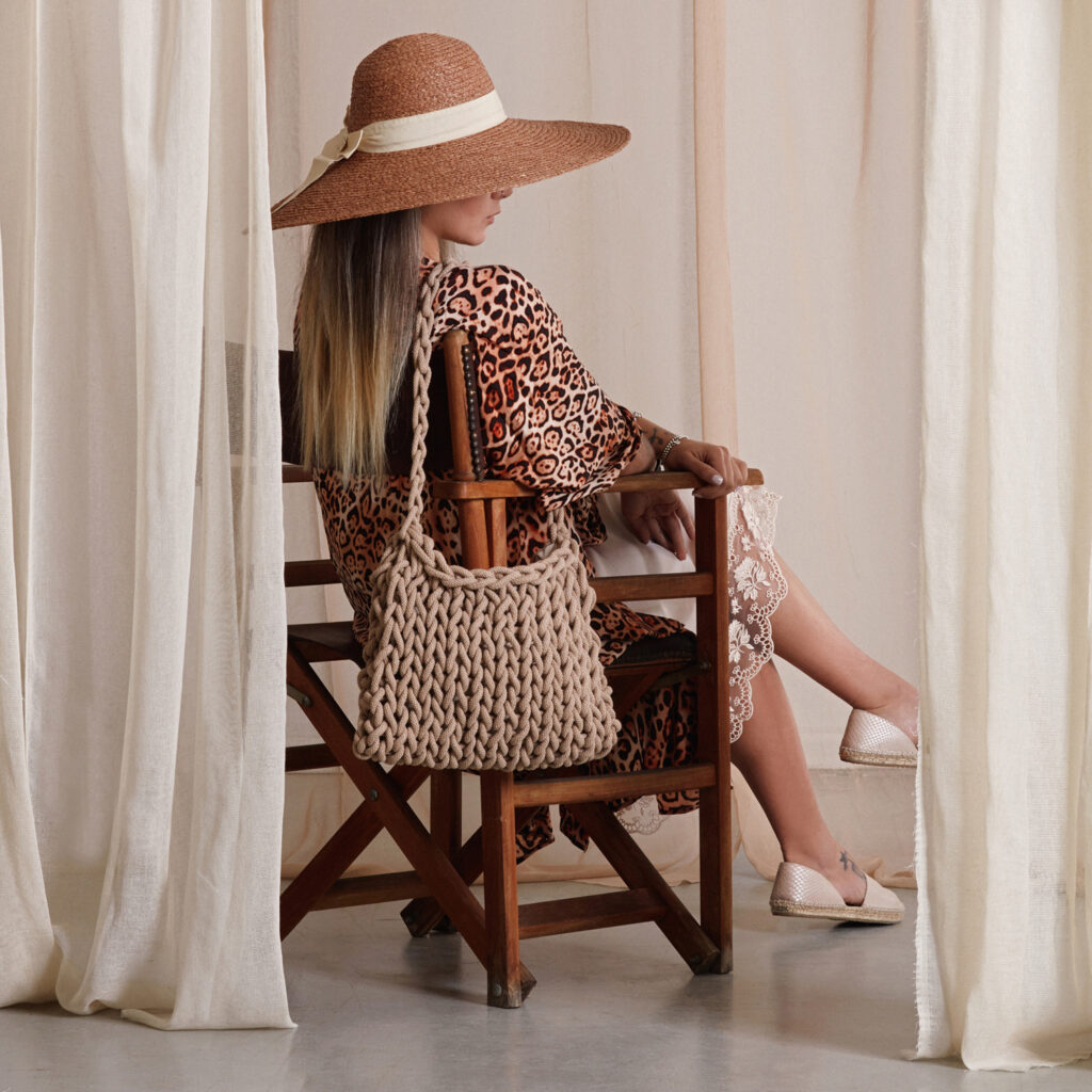 girl holds a handmade knitted shoulder bag in beige color