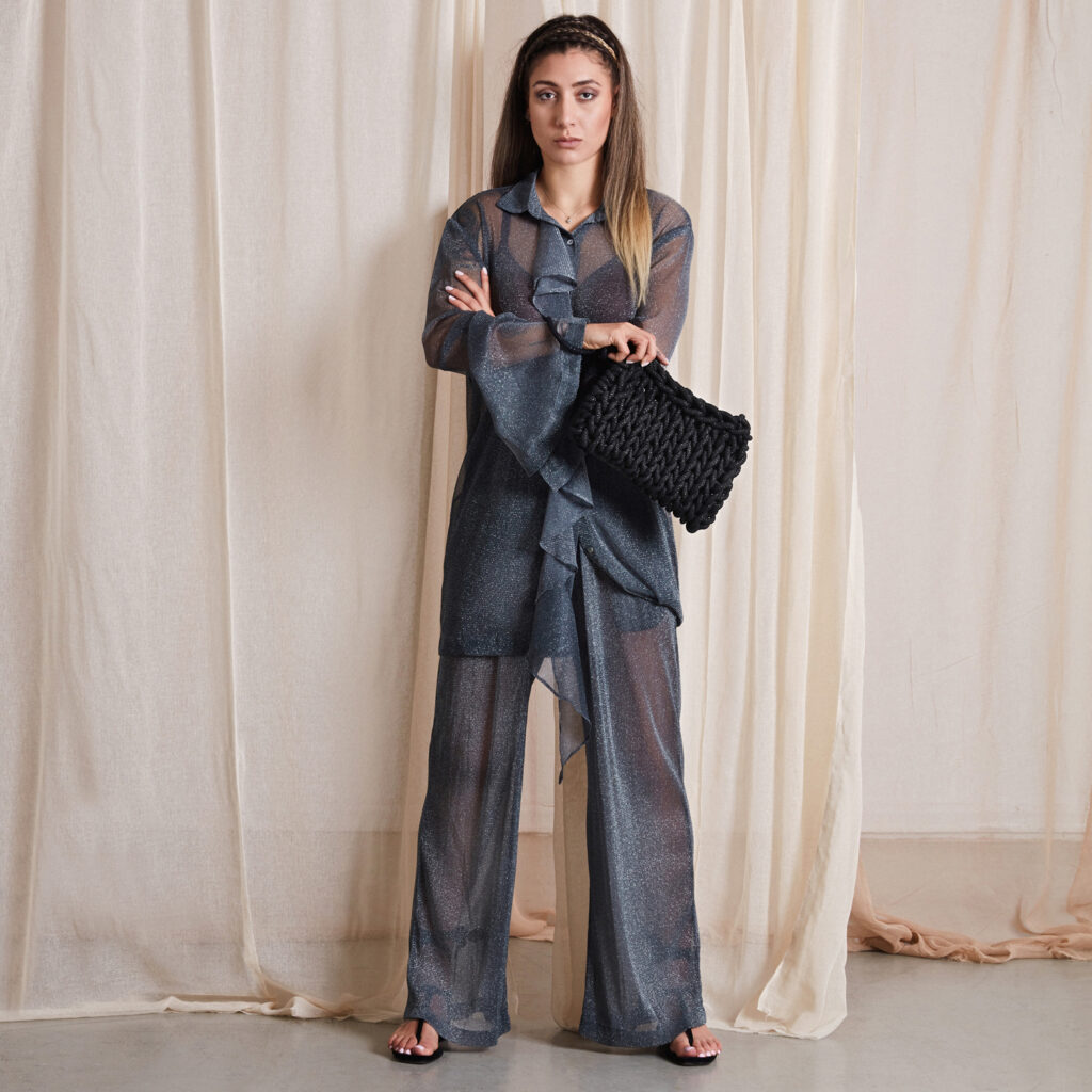 girl holds a handmade knitted clutch bag in metallic black color