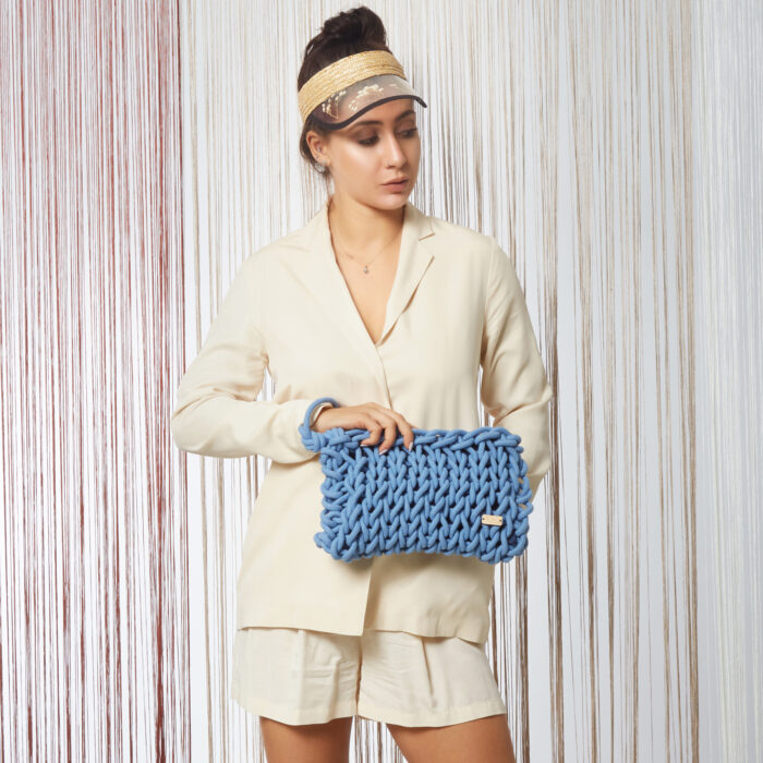 girl holds a handmade knitted clutch bag made of cotton ropes in ocean blue color