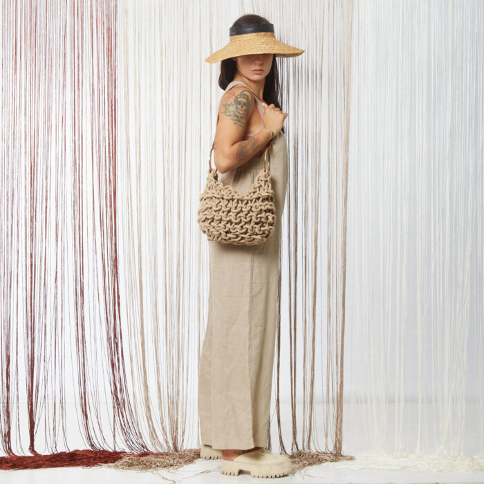 A girl holds a handmade knitted hobo bag with real leather adjustable strap, in beige color