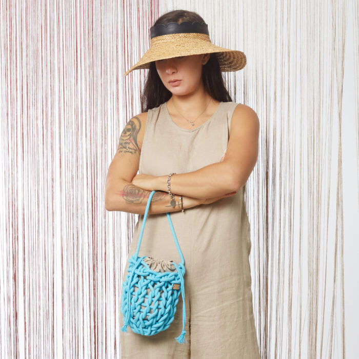 a girl holds a handmade knitted wristed bag in ocean blue color